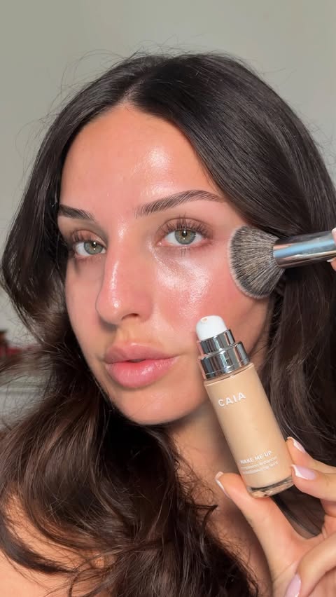 Instagram post by @naomimizrahi for CAIA COSMETICS. Caption reads: Ad summer radiance in a bottle 👀 @caiacosmetics....
