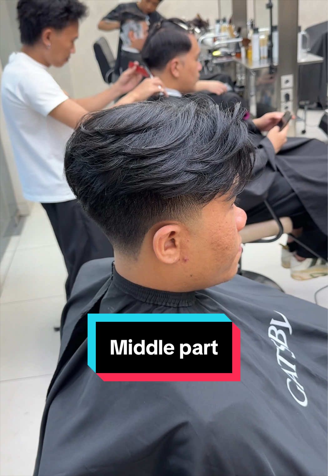 TikTok post by @aryadillah_27 for GATSBY Indonesia. Caption reads: Middle part x taper fade style with @GATSBY....