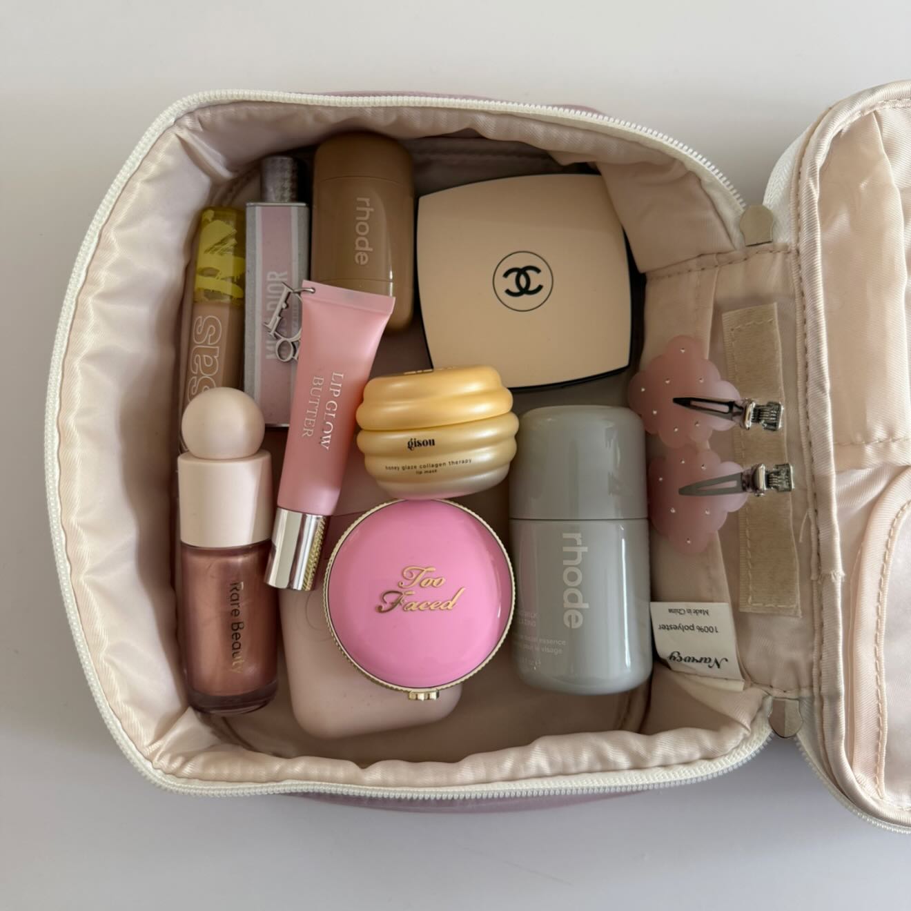 Instagram post by @carrieanne_ for Glossier. Caption reads: beauty musthaves 🩶🌸🍯 pr inc - #makeupbag....