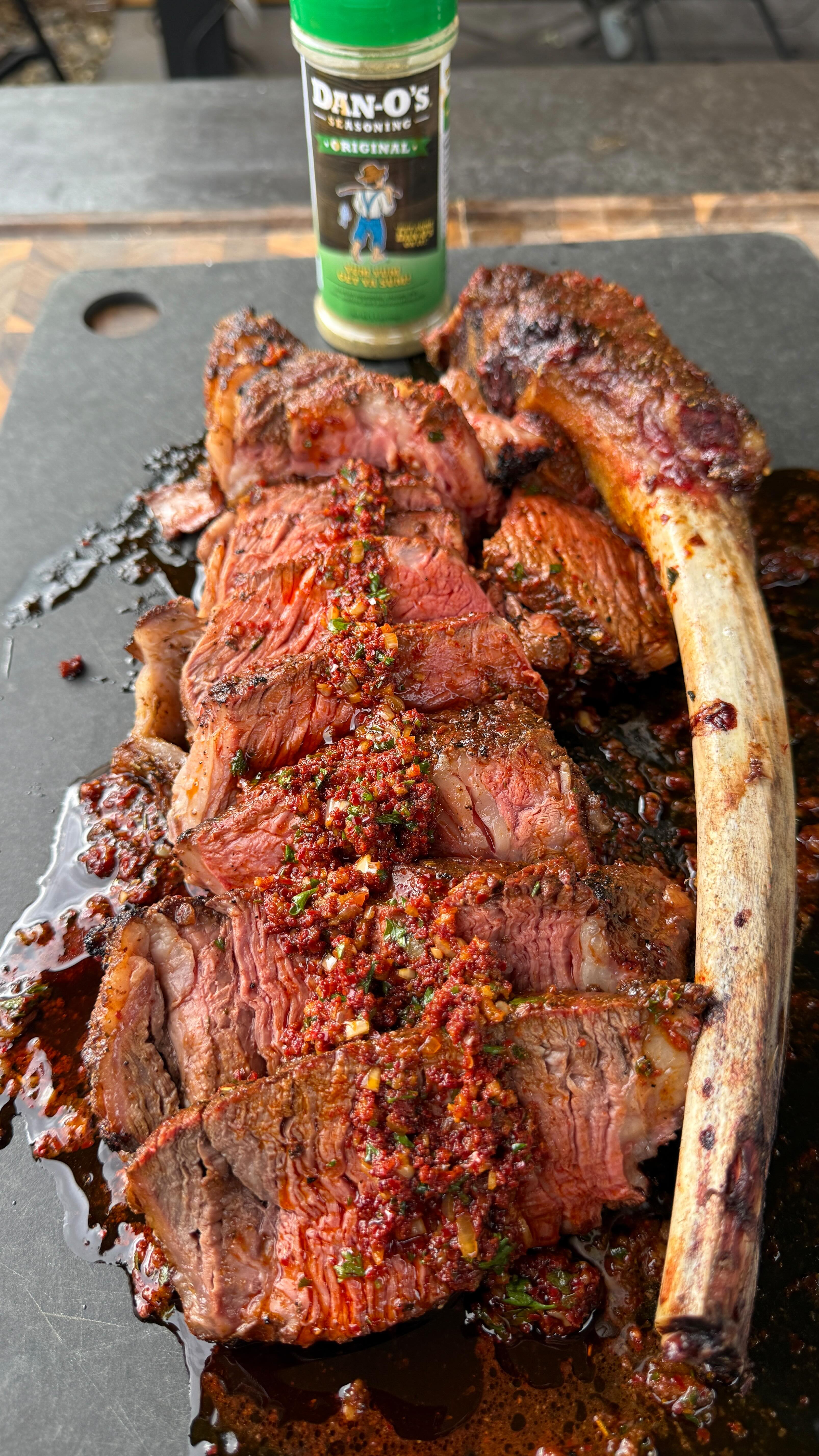 Instagram post by @cooking_with_fire___ for Dan-O's Seasoning. Caption reads: Herb crusted spicy garlic tomahawk steak with....