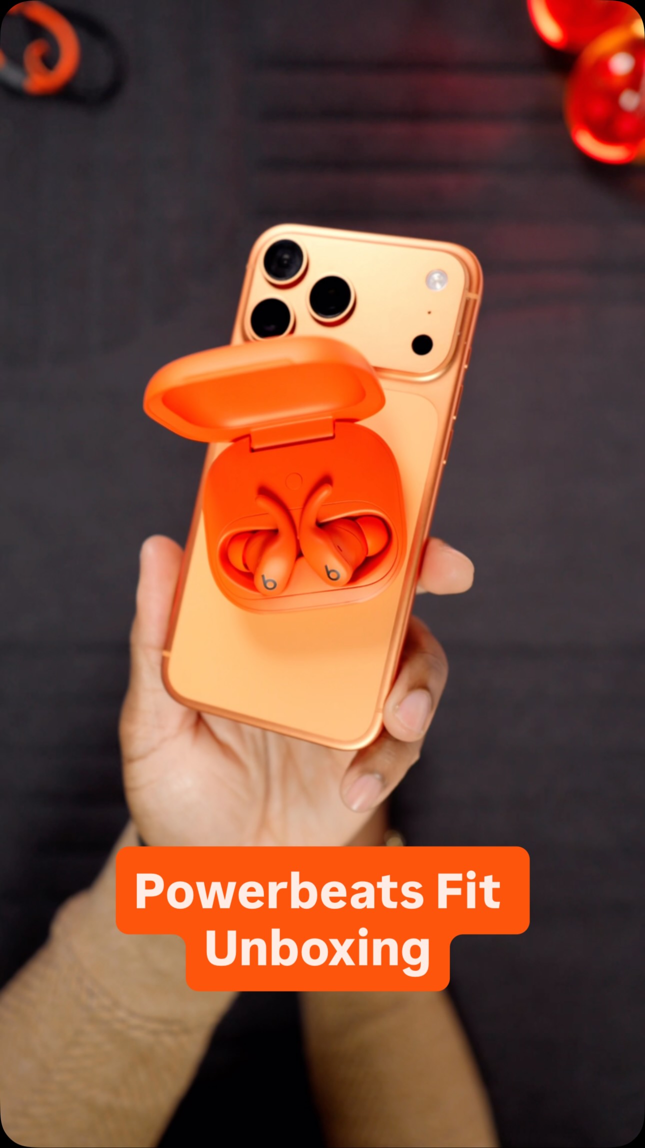 Instagram post by @uravgconsumer for Beats by Dre. Caption reads: That orange Powerbeats Fit x iPhone 17 Pro Max....