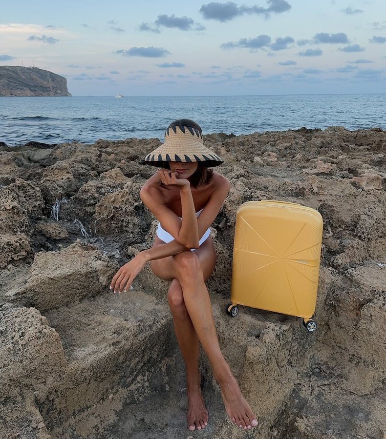 Instagram post by @carlaferrer1 for American Tourister. Caption reads: Yellow for all summer trips 
....