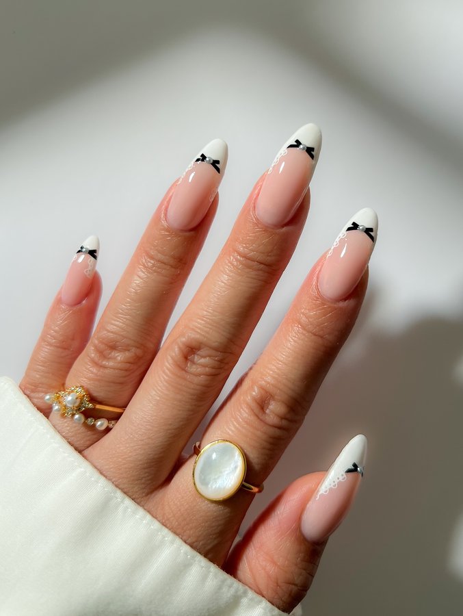 Instagram post by @mydumbnails for Caitlyn Minimalist. Caption reads: Tiny bows, lace and pearls 🤍🖤

Products....