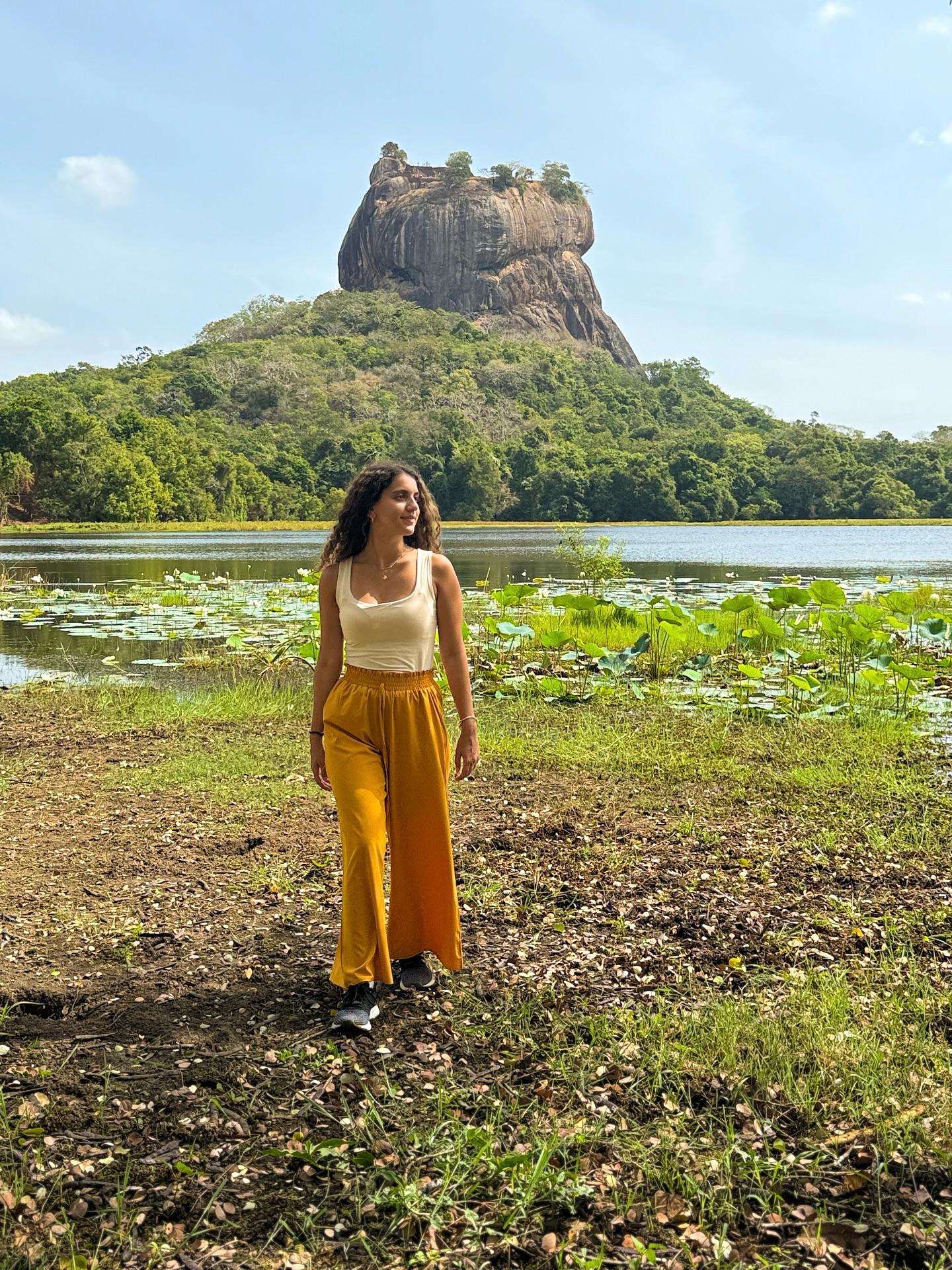 Instagram post by @mikaelitsa for Girls LOVE Travel®. Caption reads: Standing before the majestic Sigiriya Lion Rock,....