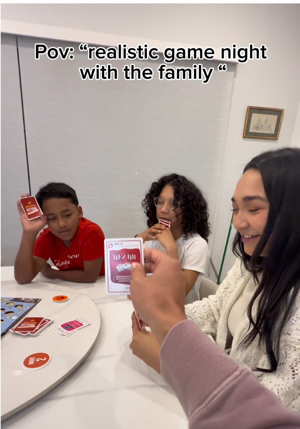 TikTok post by @ashley_annel for Exploding Kittens. Caption reads: Playing Exploding Kittens with our family! We had....