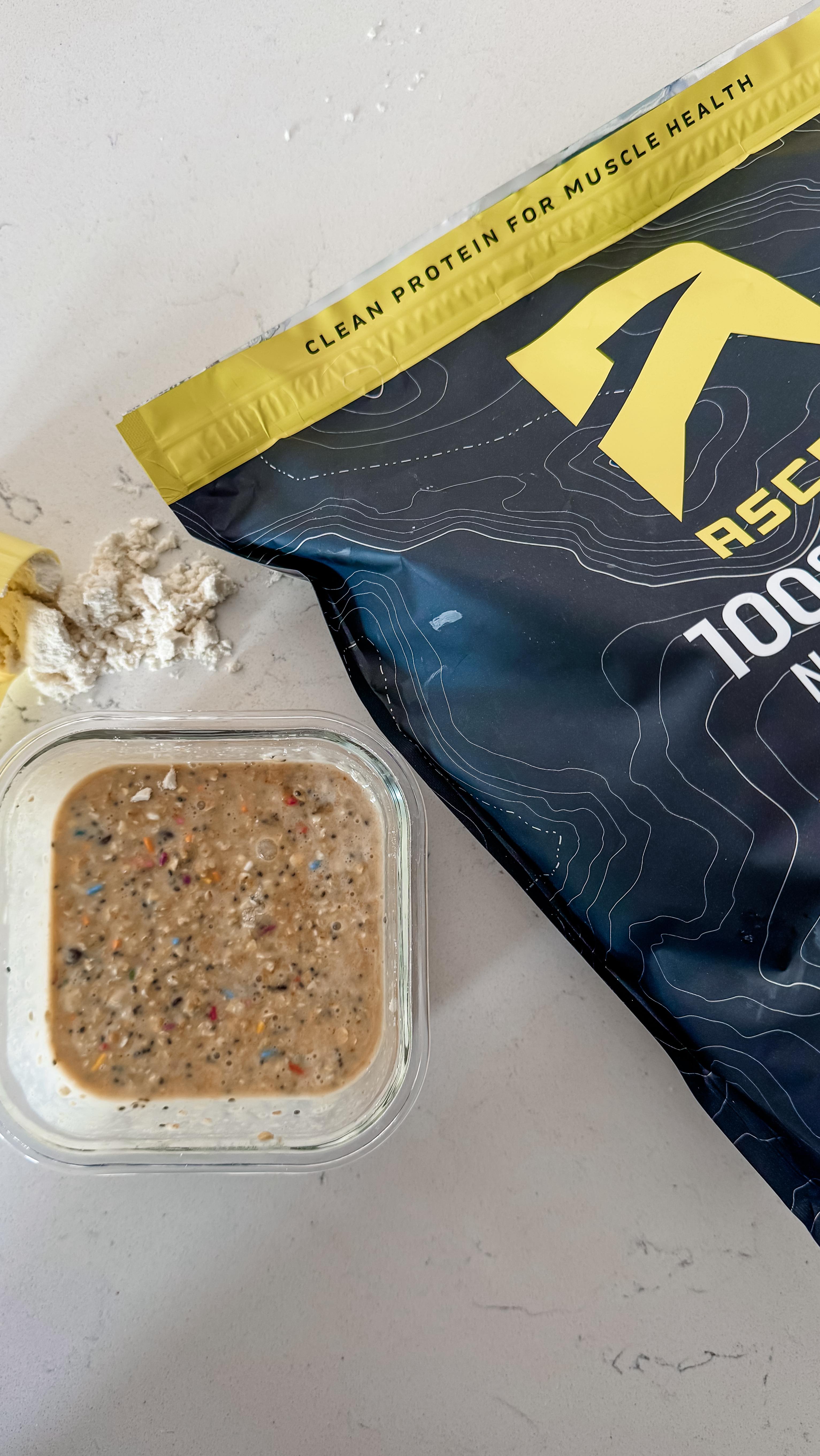 Instagram post by @k.neeekola for Ascent Protein. Caption reads: Birthday cake overnight oats that taste like....