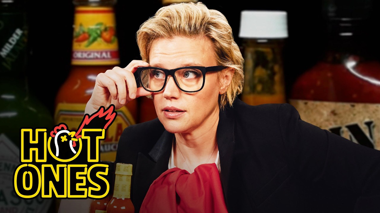 YouTube post by @FirstWeFeast for First We Feast. Caption reads: Kate McKinnon Gets Weird While Eating Spicy Wings....