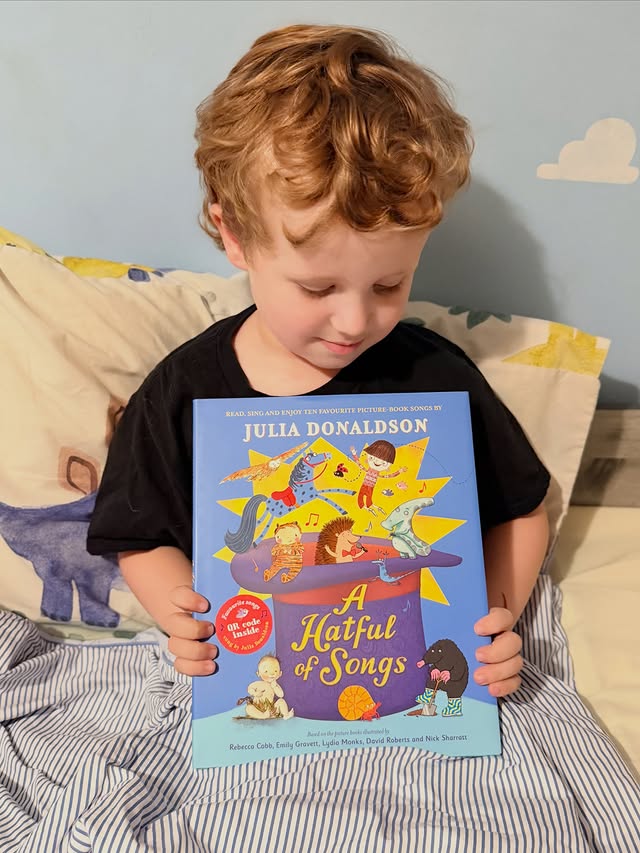 Instagram post by @elijahmama.bear for Macmillan Children's Books. Caption reads: 🎩A HATFUL OF SONGS🎩 Ad|Gifted - This beautiful....