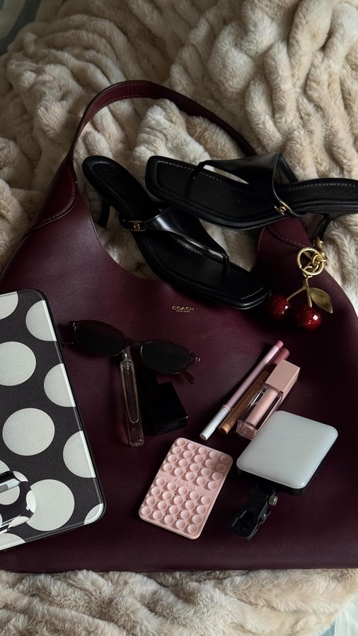 Instagram post by @achendricks for REVOLVE. Caption reads: Everything in my @coach Brooklyn Shoulder 39 bag....