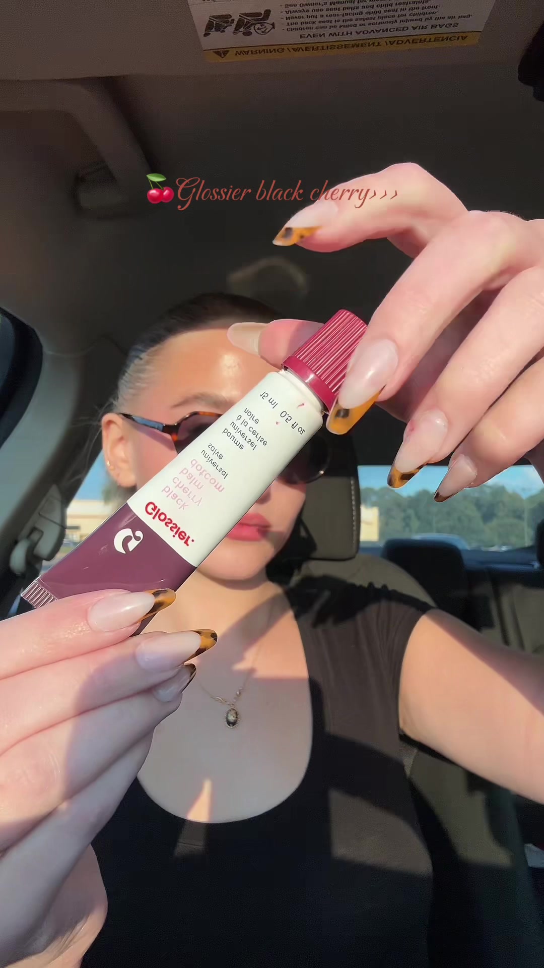 TikTok post by @makeup_by_devvynn for Glossier. Caption reads: [...] favorite fall lip balm🍒🖤 @Glossier “Black....