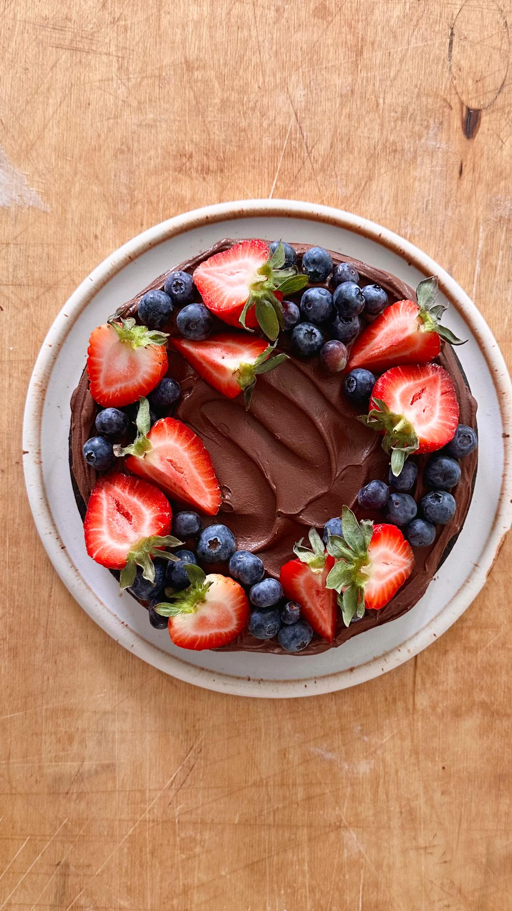 Instagram post by @bakedbydan for Harmless Harvest. Caption reads: My Chocolate Ganache and Berries Cake made with....