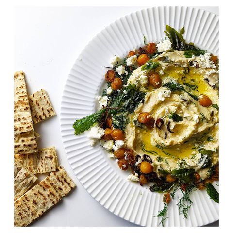 Instagram post by @thesaltychilli for NYT Cooking. Caption reads: Creamy Hummus with Fried Herbs, Feta and Crisp....