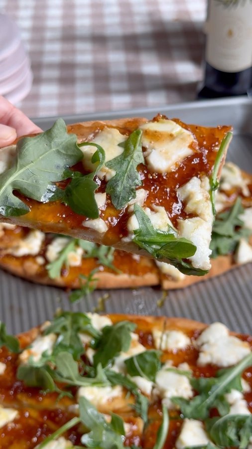 Instagram post by @dashofmandi for Mezzetta. Caption reads: Fig goat cheese arugula flatbread drizzled with....