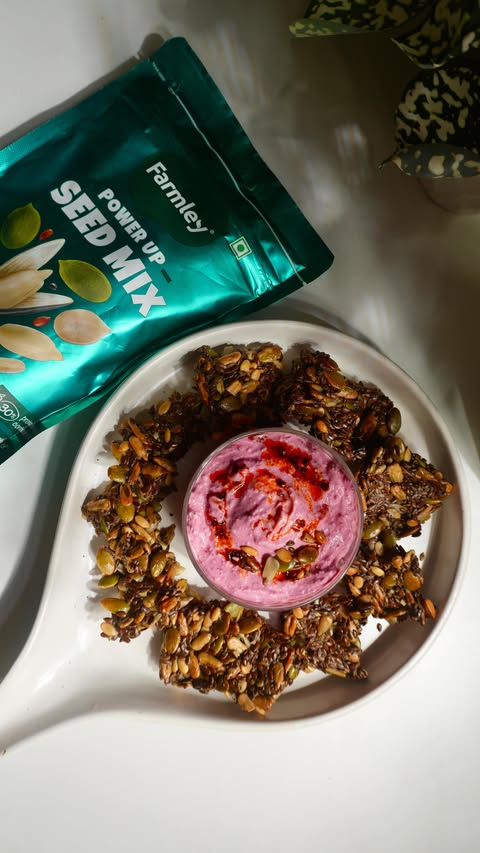 Instagram post by @thevegetarianladki for Farmley. Caption reads: Crunchy baked seed crackers made with Farmley....