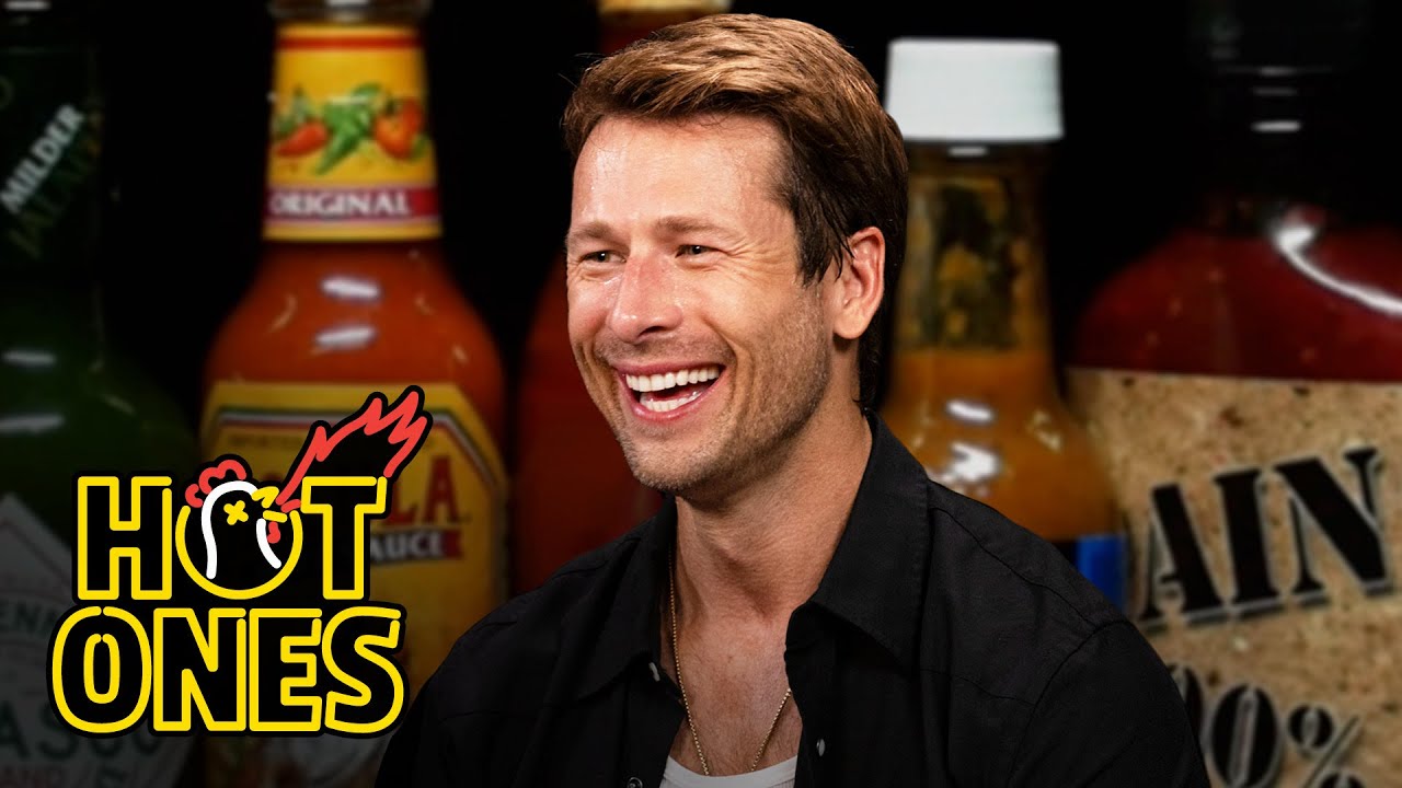 YouTube post by @FirstWeFeast for First We Feast. Caption reads: Glen Powell Needs a Wingman While Eating Spicy....