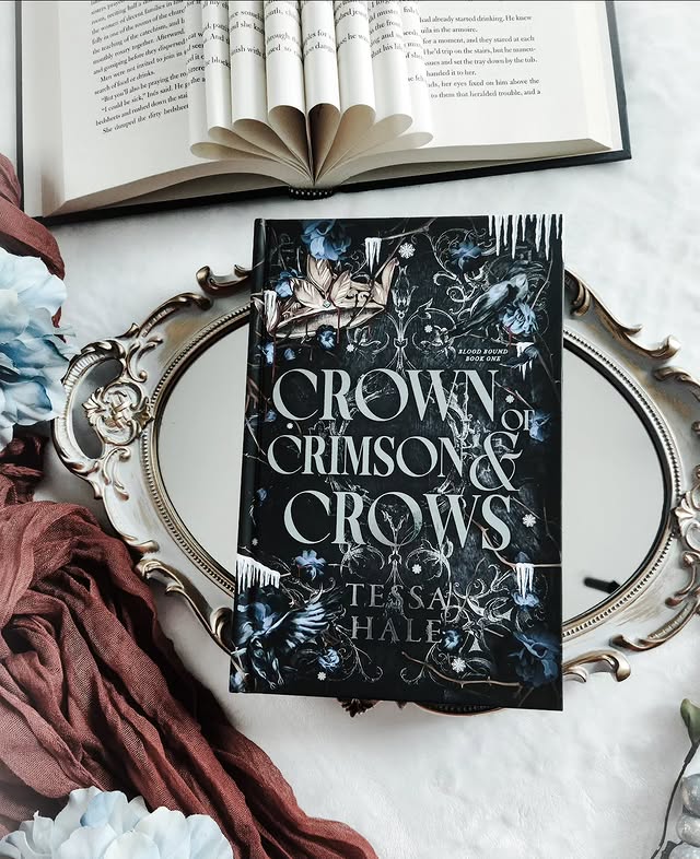 Instagram post by @deasbookshelf for Bloom Books. Caption reads: 👑 Bookmail 👑 Crown of Crimson & Crows by Tessa....