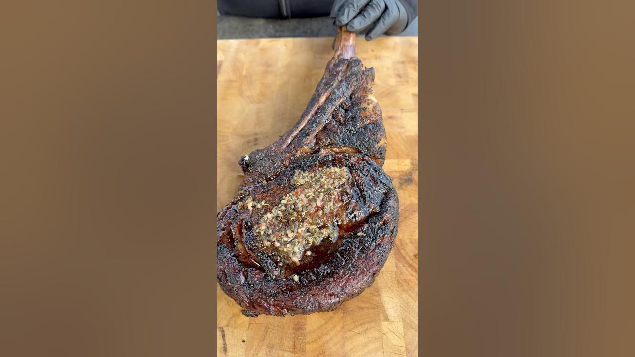 YouTube post by @miguelscookingwithfire for Monument Grills. Caption reads: Garlic and herb tomahawk steak @DanOsSeasoning.