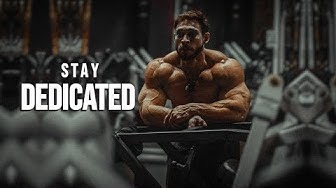 YouTube post by @MuscleBrawn for ENHANCED Labs. Caption reads: STAY DEDICATED 😈 Gym Motivation.