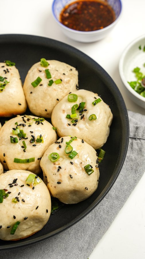 Instagram post by @onehappybite for Anolon. Caption reads: Shanghai Pan-Fried Pork Buns, or Sheng Jian Baos,....