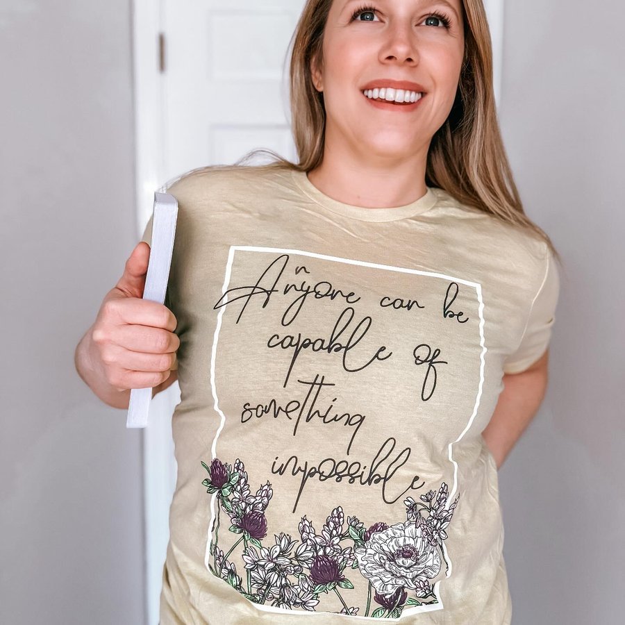 Instagram post by @buildingourbookshelves for Fae Crate. Caption reads: [...] I’m loving this tee from the January....