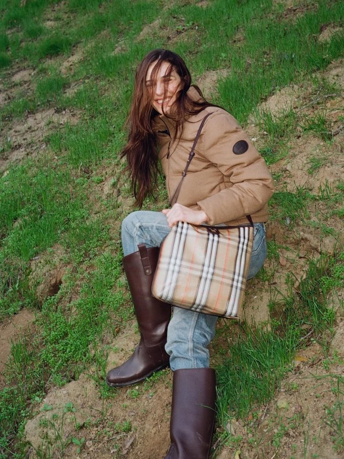 Instagram post by @devonleecarlson for Burberry. Caption reads: Touching grass 🐿️ @burberry 🍁🌲🌲🌲 #ad.