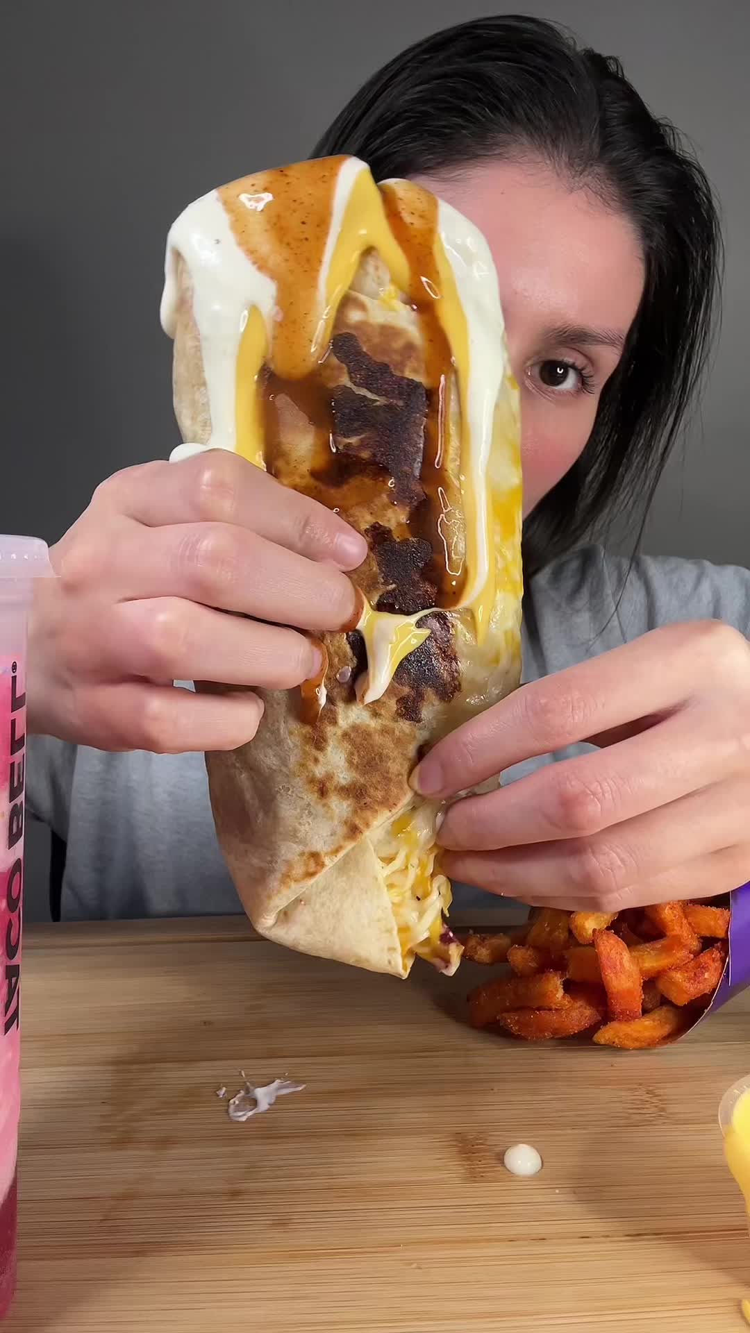 TikTok post by @kmarie.eats for Taco Bell. Caption reads: [...] And this creamy garlic sauce is 🔥 @tacobell....