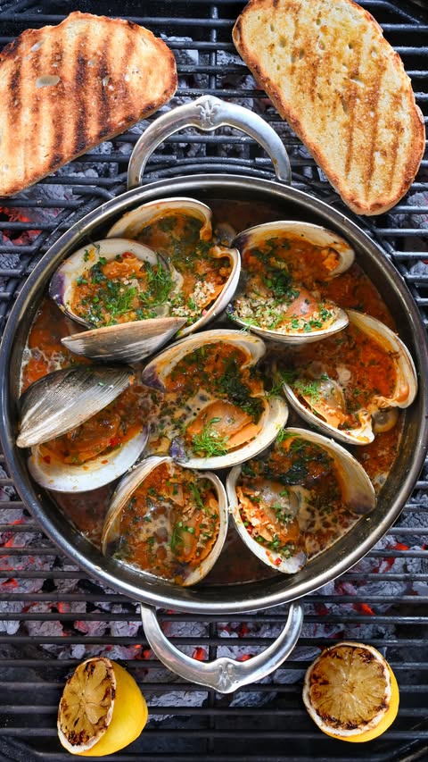Instagram post by @zimmysnook for Hestan Culinary. Caption reads: Grilled Clams Casino with Calabrian Chili Sauce....