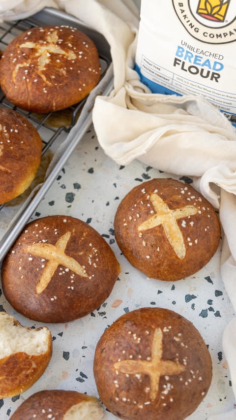 Instagram post by @milkandcardamom for King Arthur Baking Company. Caption reads: #sponsored Soft, chewy homemade pretzel buns made....